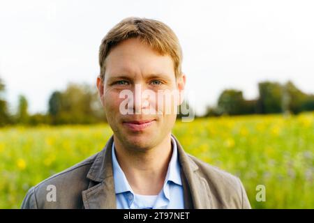 Uomo sorridente con i capelli corti nel campo Foto Stock