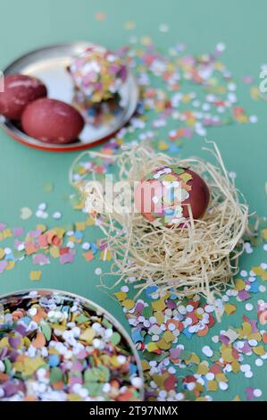 Uovo di Pasqua in nido di fieno circondato da coriandoli Foto Stock