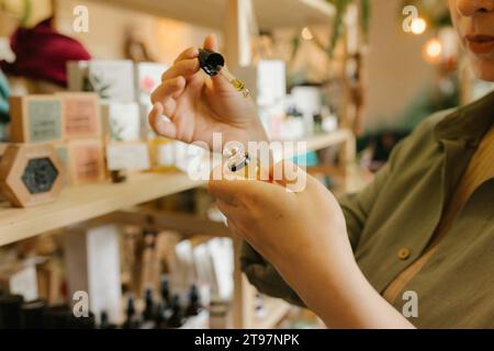 Donna che sceglie olio essenziale organico in un deposito di rifiuti zero Foto Stock