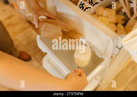 Il cliente versa il detersivo per bucato in un sacchetto di carta marrone presso l'eco-shop Foto Stock