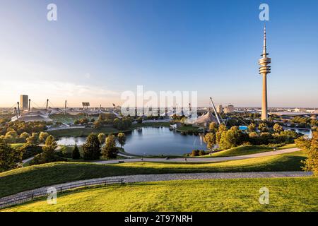 Germania, Baviera, Monaco, Parco Olimpico al tramonto con Torre Olimpica, edificio BMW e stagno sullo sfondo Foto Stock