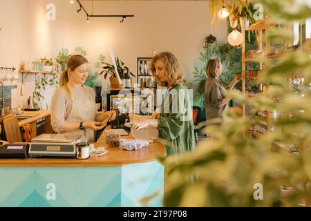 Cliente che paga al proprietario al banco cassa del negozio Foto Stock