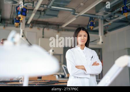 Scienziato sorridente in piedi con le braccia incrociate in laboratorio Foto Stock
