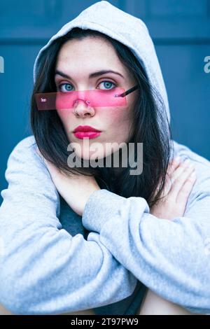 Donna che indossa una camicia con cappuccio e occhiali intelligenti Foto Stock