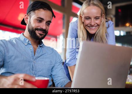 Freelance sorridenti che lavorano su un computer portatile in una caffetteria Foto Stock