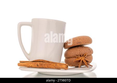 Biscotti al cioccolato, cannella, anice stellato e chicchi di caffè con tazza e piattino in ceramica, macro isolato su sfondo bianco. Foto Stock