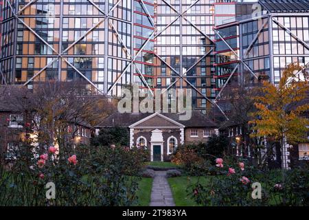 L'architettura moderna incombe su Hoptons Almshouses in Hopton Street, Southwark il 15 novembre 2023 a Londra, Regno Unito. Alti edifici in vetro si affacciano dietro queste case di importanza storica a Bankside e vicino alla Tate Modern. Fondata da Robert Hopton, pescivendolo nel 1730. Proprietà costruite intorno ad un giardino nel 1752 e sono ancora in uso. Prima dei giorni di provvigione statale per i vecchi, gli infermi o i poveri era comune per gli individui ricchi lasciare denaro o proprietà alla parrocchia locale o per istituire istituzioni indipendenti per assistere i bisognosi localmente.molte antiche parrocchie hanno tale isti Foto Stock