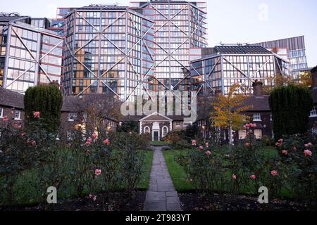 L'architettura moderna incombe su Hoptons Almshouses in Hopton Street, Southwark il 15 novembre 2023 a Londra, Regno Unito. Alti edifici in vetro si affacciano dietro queste case di importanza storica a Bankside e vicino alla Tate Modern. Fondata da Robert Hopton, pescivendolo nel 1730. Proprietà costruite intorno ad un giardino nel 1752 e sono ancora in uso. Prima dei giorni di provvigione statale per i vecchi, gli infermi o i poveri era comune per gli individui ricchi lasciare denaro o proprietà alla parrocchia locale o per istituire istituzioni indipendenti per assistere i bisognosi localmente.molte antiche parrocchie hanno tale isti Foto Stock