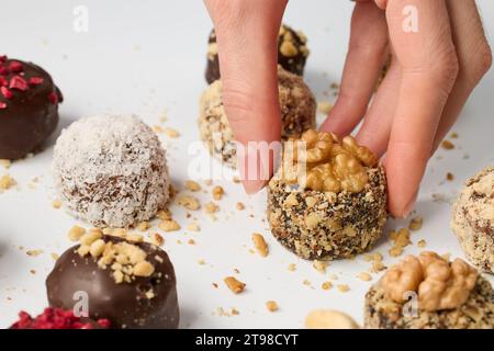 Donna che prende caramelle al cioccolato dal tavolo bianco, vista ravvicinata Foto Stock
