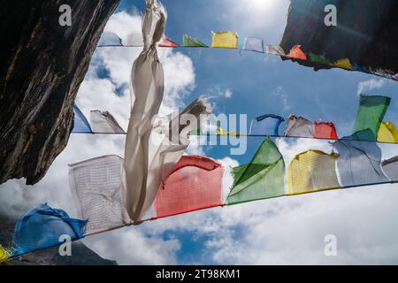 Santo buddista pregare bandiere multicolori con mantra che battono e sventolano il forte vento con cielo blu con sfondo bianco di nuvole. Makalu Barun Foto Stock