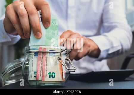 Man Hands conta le spese banconote di contante in euro da barattolo di vetro nel salvadanaio con calcolatrice. Primo piano di mani un uomo d'affari irriconoscibile. Risparmia sul concetto di investimento di budget. Euro finanzia filmati di risparmio Foto Stock