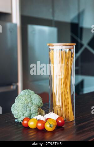 Immagine di natura morta di un tavolo da cucina con una varietà di pasta italiana e verdure fresche Foto Stock