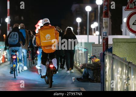 Groningen, Paesi Bassi - 11 17 2023: Persona che effettua il recapito flash da Thuisbezorgd in bicicletta in una grande città che passa davanti all'elemosina Foto Stock