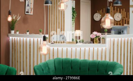 Area lounge tropicale vuota dell'hotel con divano di lusso e banco ricevimento moderno, interni dal design elegante. La lobby del ricevimento e' decorata con orologi e luci fresche, spazio lussuoso con piante. Foto Stock