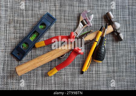 Utensili utilizzati per lavori domestici, livella a bolla d'aria, chiave regolabile, pinze, martello, cacciavite, penna. Foto Stock