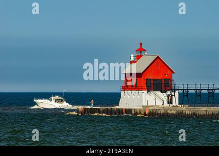 Il Muskegon North Pier Pierhead Lighthouse viene mostrato con un'imbarcazione da diporto che corre fuori dal porto, Muskegon, contea di Muskegon, Michigan Foto Stock