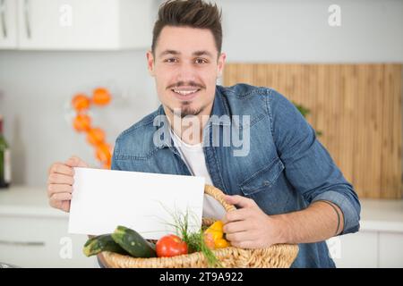 bell'uomo che tiene un foglio di carta in cucina Foto Stock