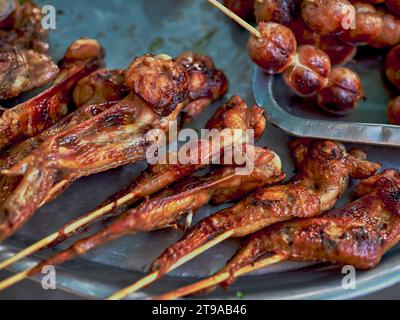 Street food tailandese al mercato. Isaan Sausages. E pollo alla griglia sul piano cottura Foto Stock