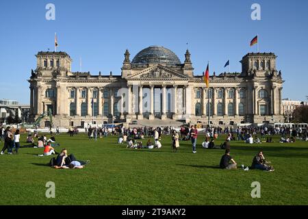 Berlino, Germania - 30 ottobre 2022: La gente si rilassa sul gras vicino al Bundestag tedesco (edificio del Reichstag) è il parlamento nazionale della federazione Foto Stock