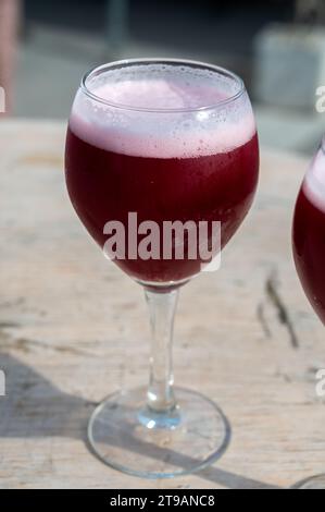 Famosa birra rossa lambic kriek, birra alla ciliegia fresca servita all'aperto nel festival belga della birra a Durbuy, speciale bicchiere di birra belga alle luci del sole, vicino a u Foto Stock