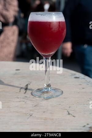 Famosa birra rossa lambic kriek, birra alla ciliegia fresca servita all'aperto nel festival belga della birra a Durbuy, speciale bicchiere di birra belga alle luci del sole, vicino a u Foto Stock