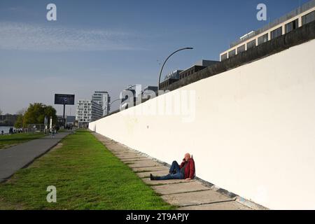 Berlino, Germania - 31 ottobre 2022: Un uomo rilassati vicino alle mura di Berlino nella East Side Gallery. Foto Stock