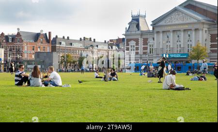 Amsterdam, Paesi Bassi – 9 ottobre 2022: I giovani si godono il sole a Museumplein al tramonto Foto Stock