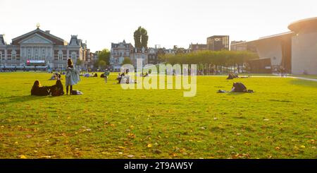 Amsterdam, Paesi Bassi – 9 ottobre 2022: I giovani si godono il sole a Museumplein al tramonto Foto Stock