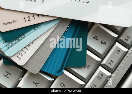 Primo piano di più carte di credito impilate sulla tastiera di un notebook, che enfatizza i pagamenti online e la sicurezza finanziaria Foto Stock