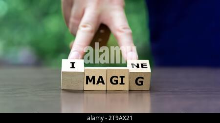 La mano gira cubi di legno e cambia la parola magia per immaginare. Foto Stock