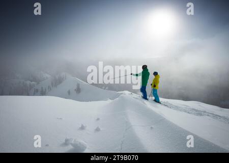 Due sciatori adulti su una cresta che si affaccia sulle montagne. Foto Stock