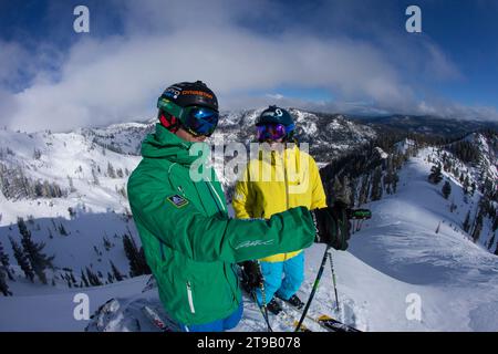 Due sciatori adulti su una cresta che si affaccia sulle montagne. Foto Stock