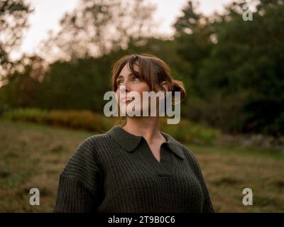 Donna in un campo boschivo autunnale, che guarda penosamente. Foto Stock