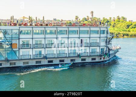 I venditori di tessuti sulle loro barche si avvicinano a una nave da crociera in attesa di entrare nella chiusa di Esna. I venditori sperano di vendere beni ai turisti. Esna, Egitto – 20 ottobre Foto Stock