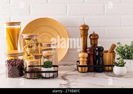 Splendido sfondo della cucina con vano portaoggetti per prodotti sfusi e spezie. Piante da interni per un'intimità. Vista frontale. Muro di mattoni bianchi Foto Stock