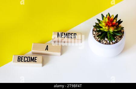 Su uno sfondo giallo brillante sono presenti blocchi di legno con l'iscrizione DIVENTA MEMBRO. Foto Stock