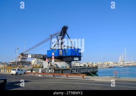 2023 luglio Rimini, Italia: Primo piano della gru blu nel porto di Rimini attraverso le barche e le navi nel porto Foto Stock