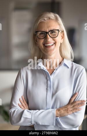 Ritratto verticale di donna d'affari anziana e bionda felice ed elegante Foto Stock