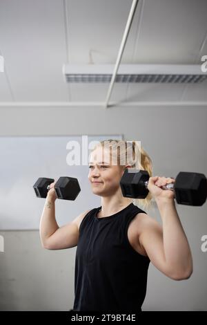 Sorridente giovane bella donna che si appoggia su anelli di ginnastica al centro benessere Foto Stock