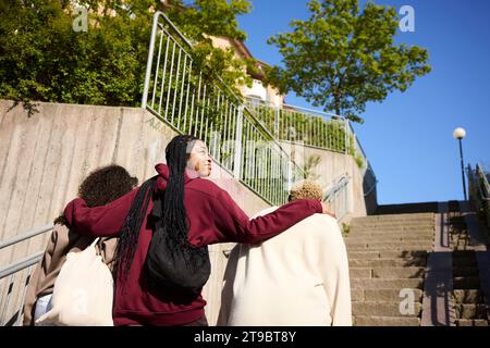 Vista dall'angolo basso di una giovane donna che sorride mentre si muove con gli amici sulle scale Foto Stock