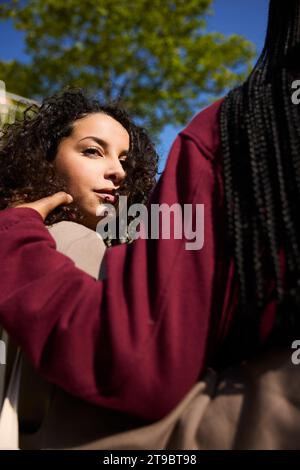Vista angolare bassa di una giovane donna con un braccio intorno a un'amica Foto Stock