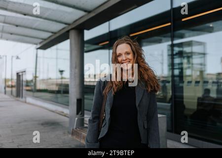 Ritratto di una donna sorridente pendolare in piedi alla stazione ferroviaria Foto Stock