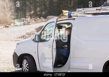 Una donna sorridente che siede sul furgone nelle giornate di sole Foto Stock