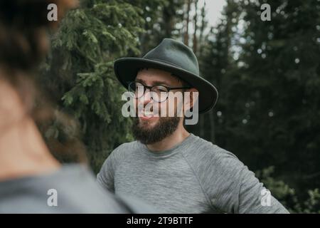 Uomo barbato sorridente che indossa occhiali e cappello Foto Stock