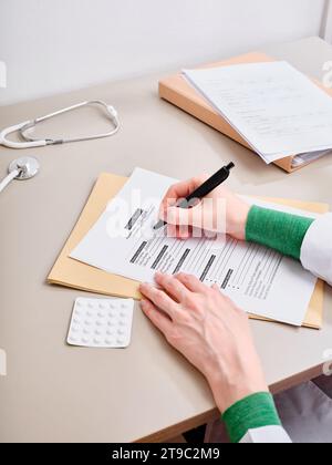 Vista dall'alto medico irriconoscibile prendere appunti nella documentazione medica presso la clinica Foto Stock