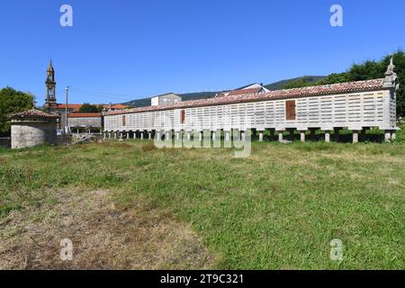 Tradizionale granaio (horreo) di pietra di granito. In fondo alla chiesa di San Mamede e a sinistra. Carnota, A Coruna, Galizia, Spagna. Foto Stock