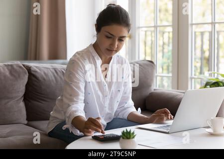 Una donna indiana seria gestisce il budget, fa il lavoro di contabilità a casa Foto Stock