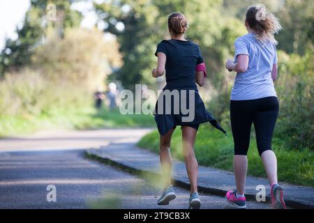 due runner donne che fanno jogging in una giornata di sole in un ambiente verde Foto Stock