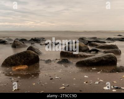 Il balletto della natura si snoda nel tranquillo abbraccio del mare, dove il tempo si ferma tra la danza delle rocce, catturate dai graziosi colpi di un l Foto Stock