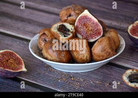 Torte di profiteroles fatte in casa con crema di cacao e gocce di cioccolato. Pasta choux, crema tagliata a metà, fichi a metà. tavolo in legno, sfondo rustico. Foto Stock